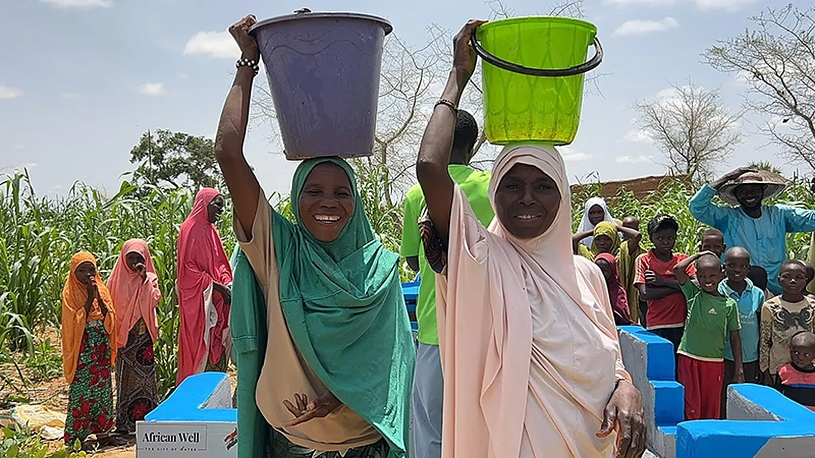 Women carrying water from a new well, with their community